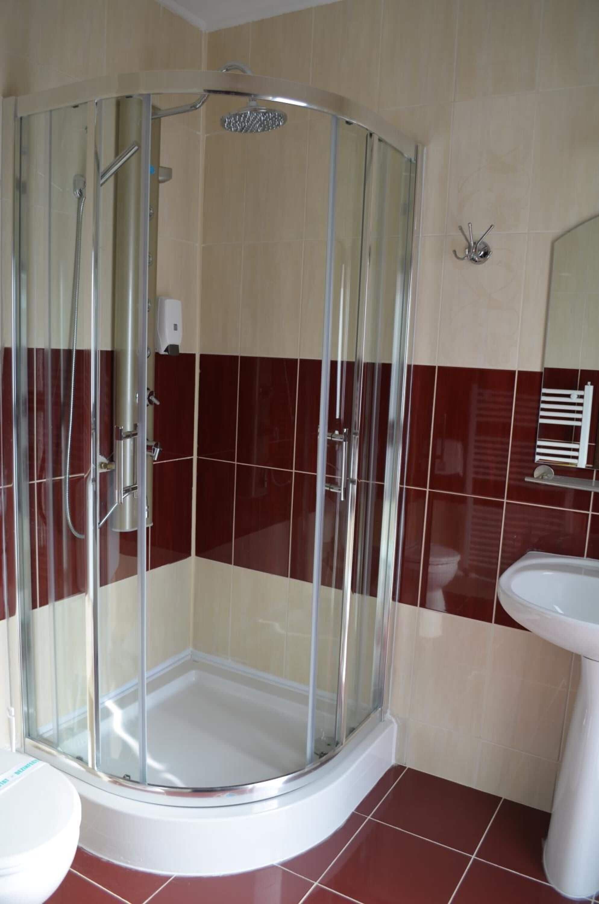 Un baño con ducha de vidrio, lavamanos blanco y retrete.