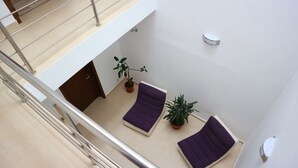 Un intérieur moderne avec un canapé violet, une plante en pot et un escalier.
