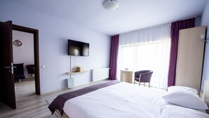 Une chambre d’hôtel avec un grand lit, un téléviseur fixé au mur, un bureau et une chaise.