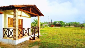 A small house with a porch and a grassy yard. - Pousada Delicia de Sono (Cajueiro da Praia)
