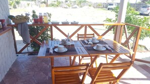Mesa de madera para cuatro personas, con platos, tazas y cubiertos.