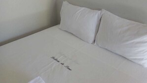 A neatly made bed with white linens and pillows, and a handwritten note on the bedspread. - Pousada Delicia de Sono (Cajueiro da Praia)