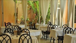 A restaurant with tables and chairs, some with white tablecloths, and a view of greenery outside. - Hôtel Narcis - Adults Only (Nabeul)