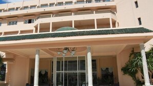 A hotel entrance with a covered area, columns, and a large glass door. - Hôtel Narcis - Adults Only (Nabeul)