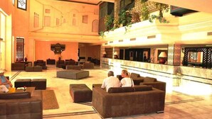A spacious lobby with multiple seating areas, a reception desk, and a high ceiling with decorative elements. - Hôtel Narcis - Adults Only (Nabeul)