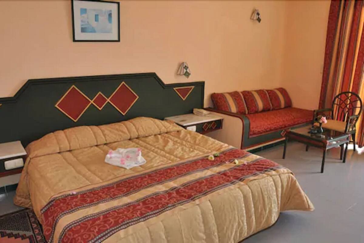 Une chambre d’hôtel avec un grand lit, un canapé, une petite table et une chaise.