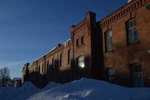 Un edificio de ladrillo con ventanas amplias y el suelo cubierto de nieve.
