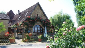 A stone building with a sloped roof, a wooden fence, and potted plants. - Lo Gorissado - La Ferme du Glandier (Saint-Andre-d'Allas)