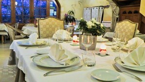 A dining area with tables set for a meal, featuring white tablecloths, plates, cutlery, and candles. - Lo Gorissado - La Ferme du Glandier (Saint-Andre-d'Allas)