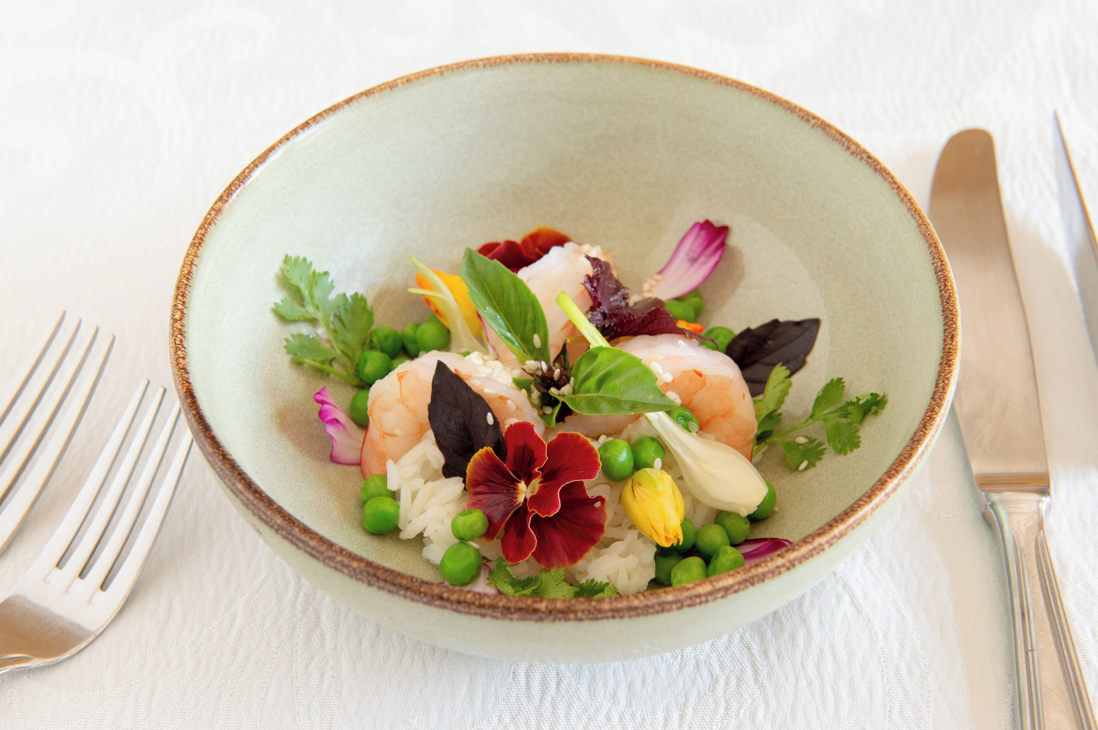 Un plato de comida con arroz, guisantes, camarones y diversas verduras.