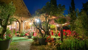 A well-lit garden area with potted plants and a covered seating area. - Lo Gorissado - La Ferme du Glandier (Saint-Andre-d'Allas)