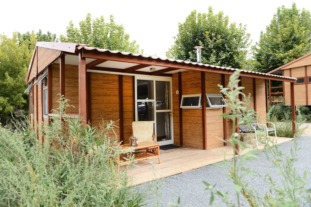 Une petite cabane en bois dotée d’un porche abrité, d’une porte-fenêtre coulissante et d’un banc.