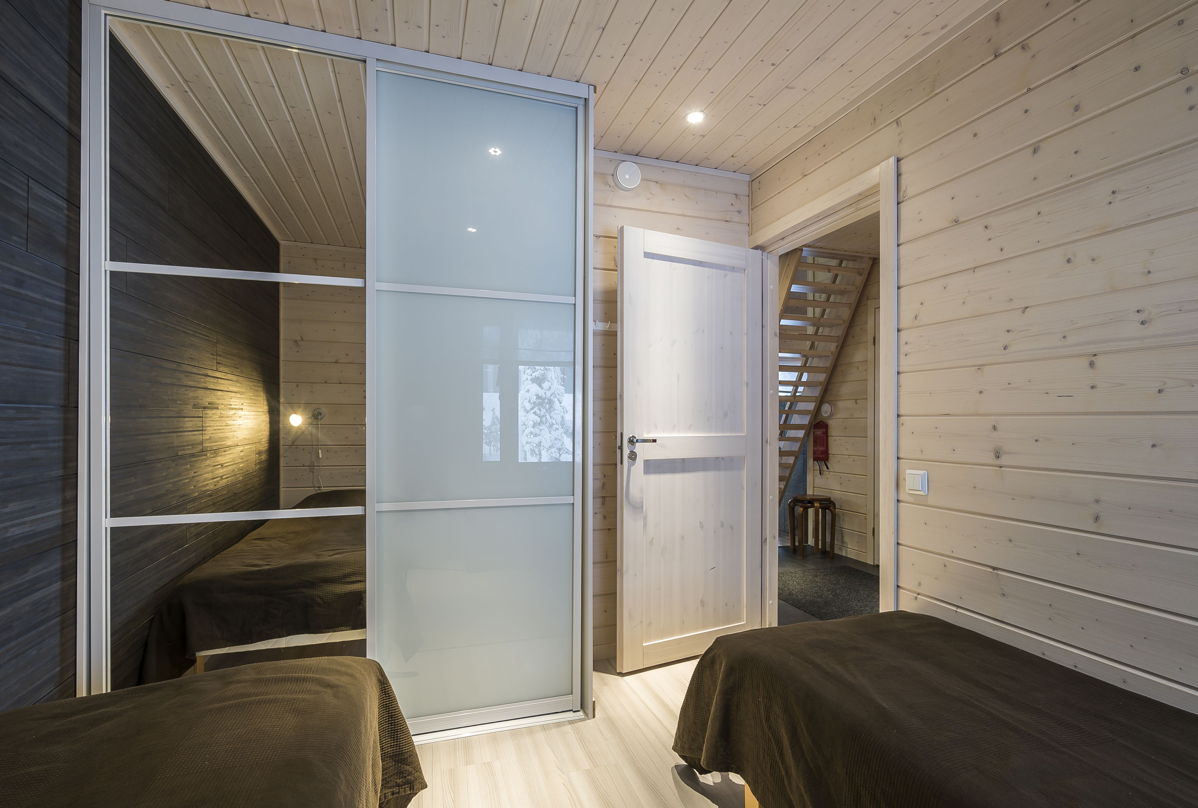 Een slaapkamer met twee bedden, een schuifdeur en een houten plafond.