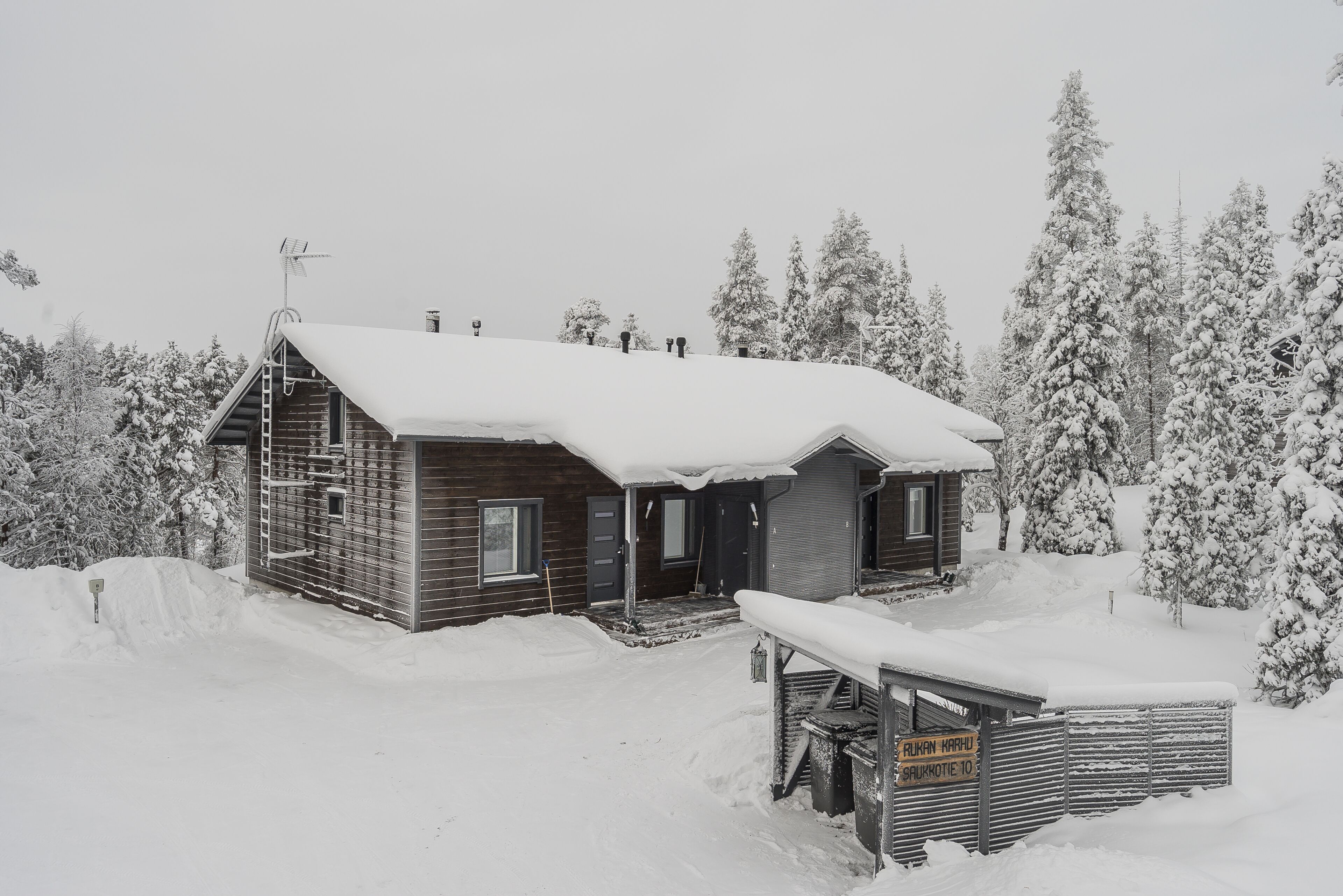 A wooden cabin with a snow-covered roof and a small porch.
