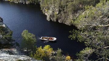 Un bote en un río tranquilo rodeado de acantilados rocosos y un bosque denso.