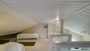 A bedroom with two beds, a wooden ceiling, and a small window.