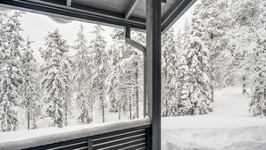 Un paysage enneigé avec une structure en bois dotée d’une fenêtre à persiennes.