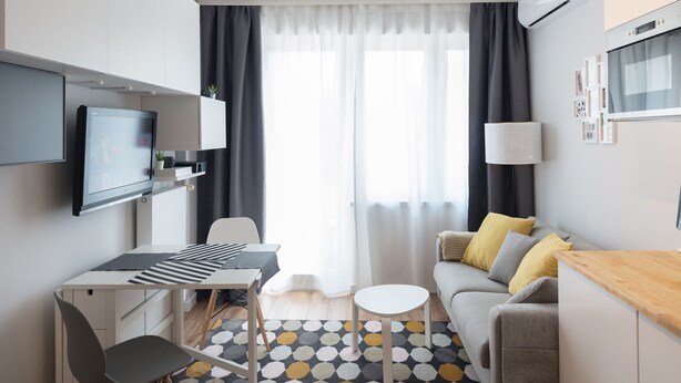 A modern living room with a flat-screen TV, a dining table, a sofa, and a coffee table. - WE Apartments (Warsaw)