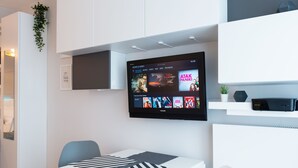 A modern living room with a flat-screen TV mounted on the wall displaying a movie selection. - WE Apartments (Warsaw)