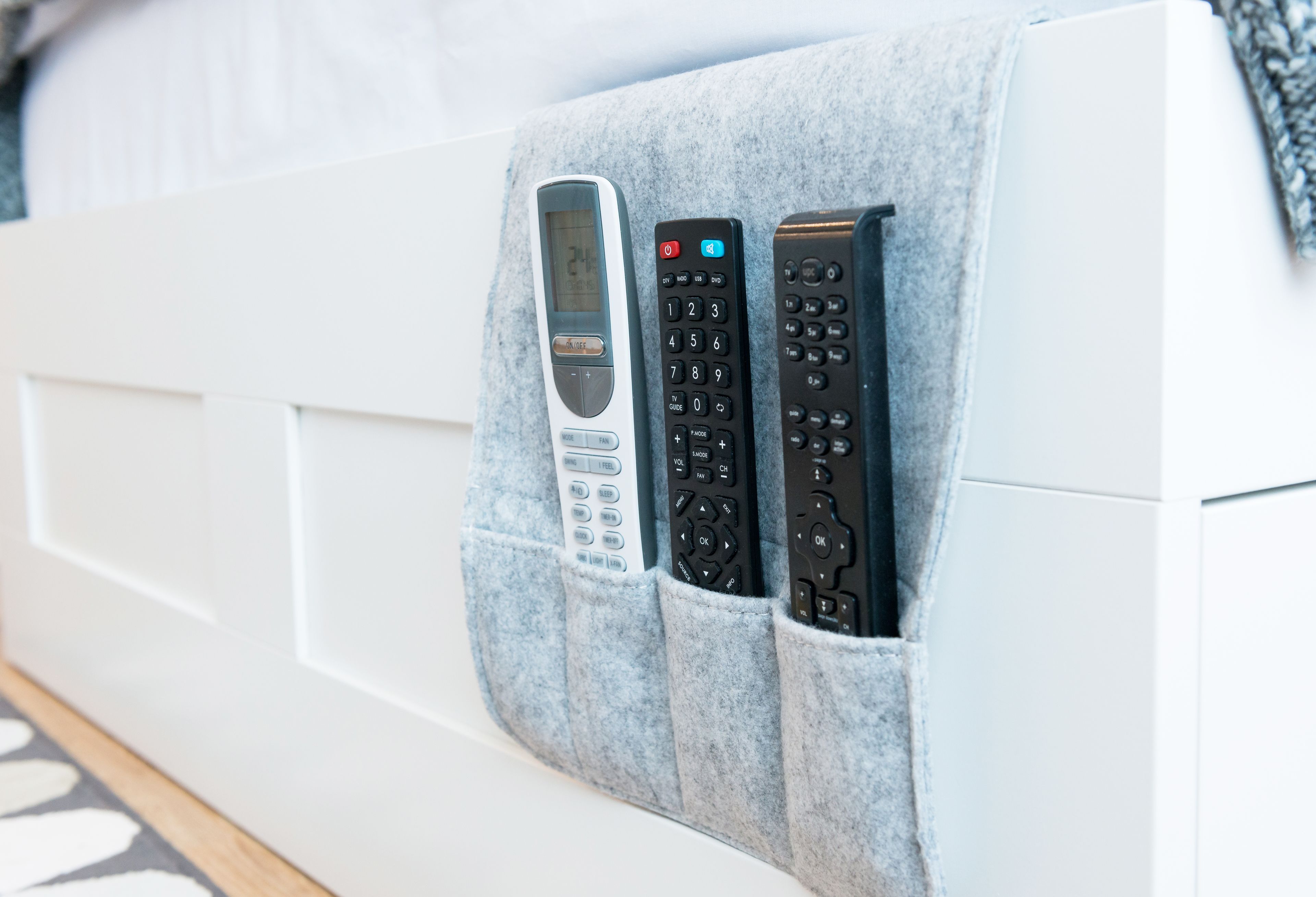 A bed with a remote control holder attached to the headboard.