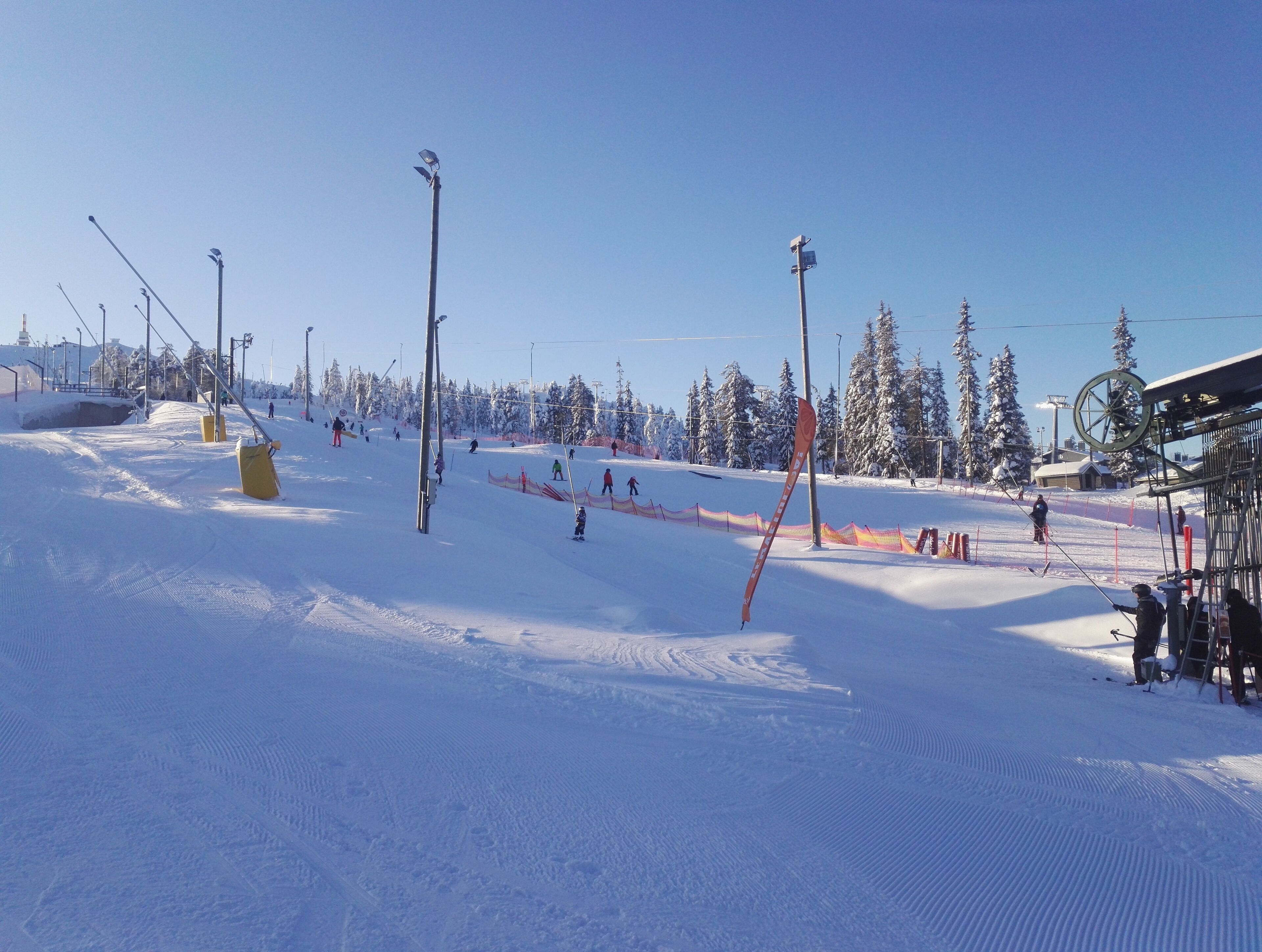 Pista de esqui com trilhas demarcadas, um teleférico e paisagem coberta de neve.