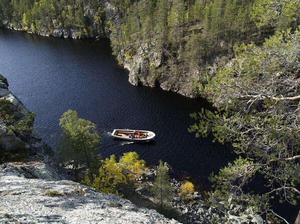Un bote en un río tranquilo rodeado de acantilados rocosos y un bosque denso.