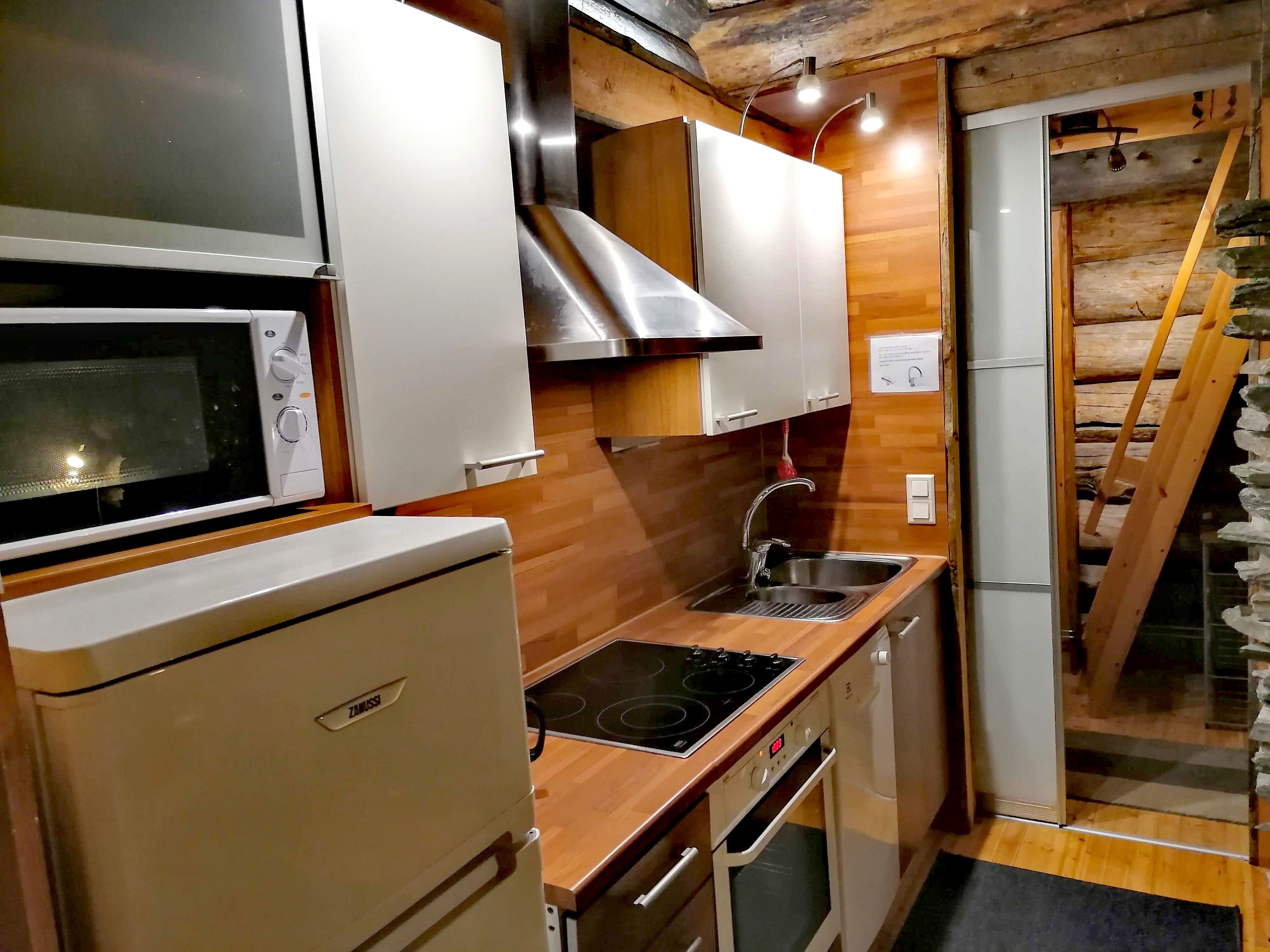 Una cocina compacta equipada con microondas, estufa, pileta y horno empotrado.
