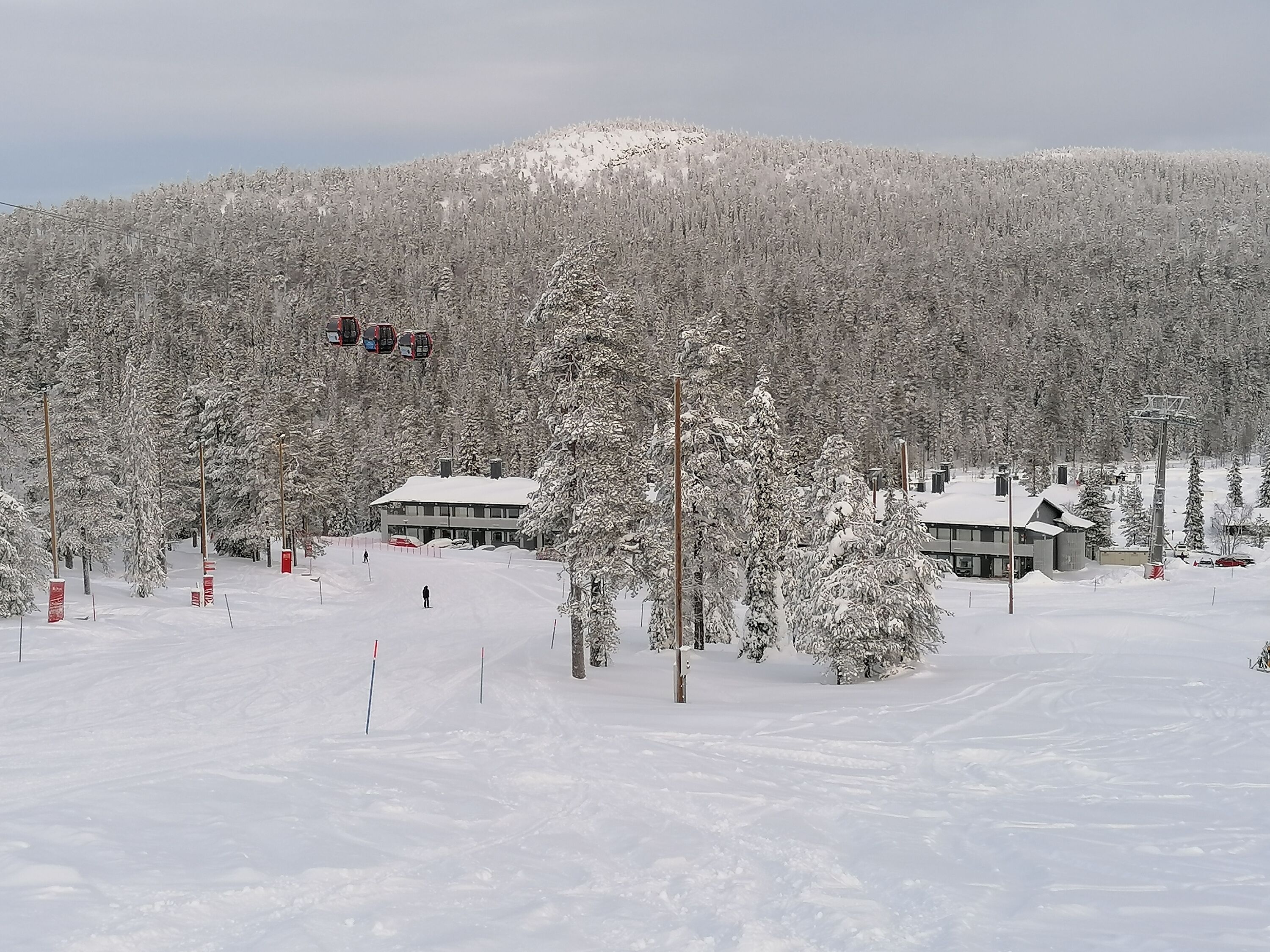 Estación de esquí cubierta de nieve con edificios y árboles.