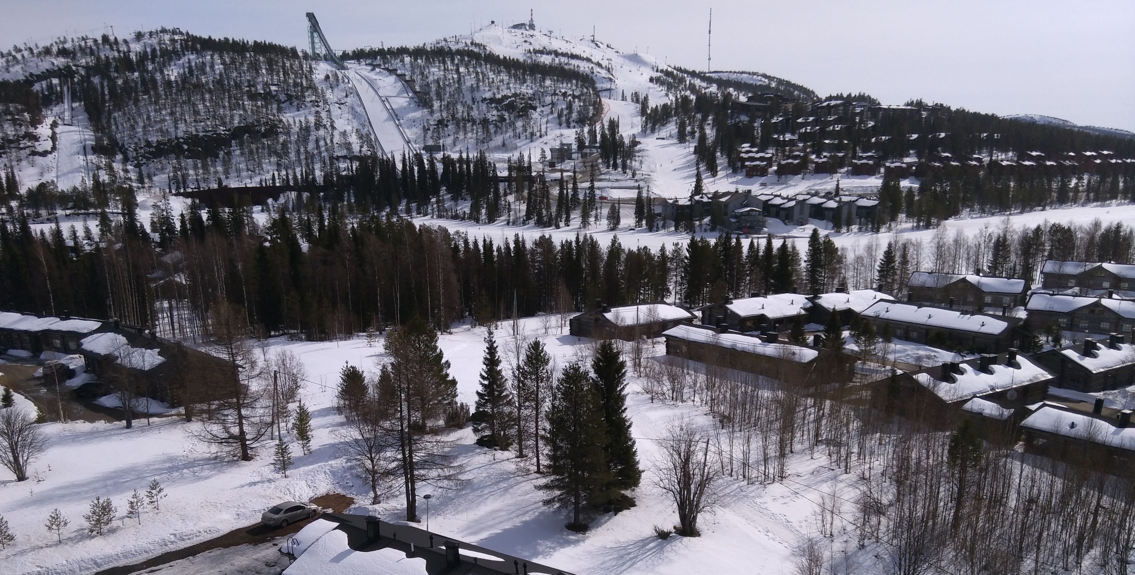 A snow-covered mountain with a ski lift and a residential area with houses.