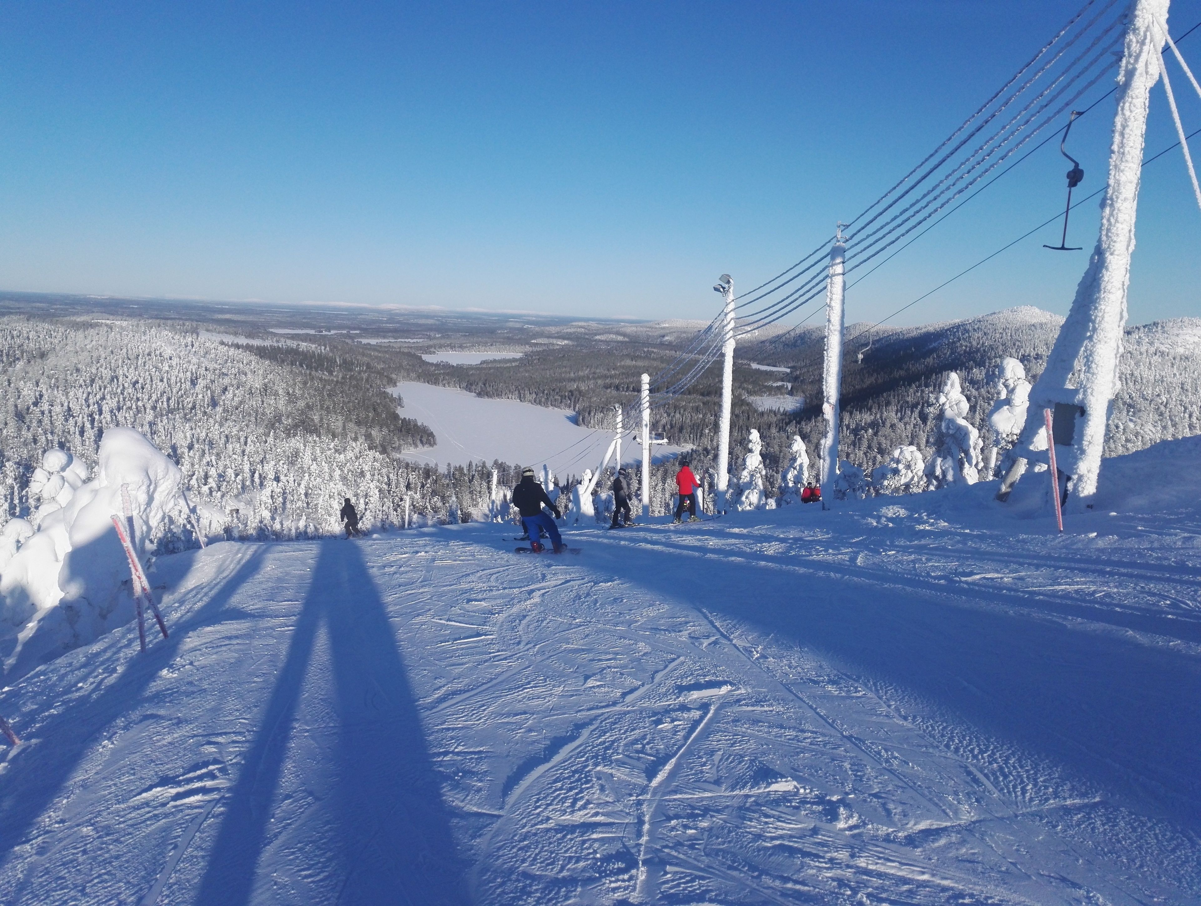 A ski slope with skiers, a clear sky, and a snowy landscape.