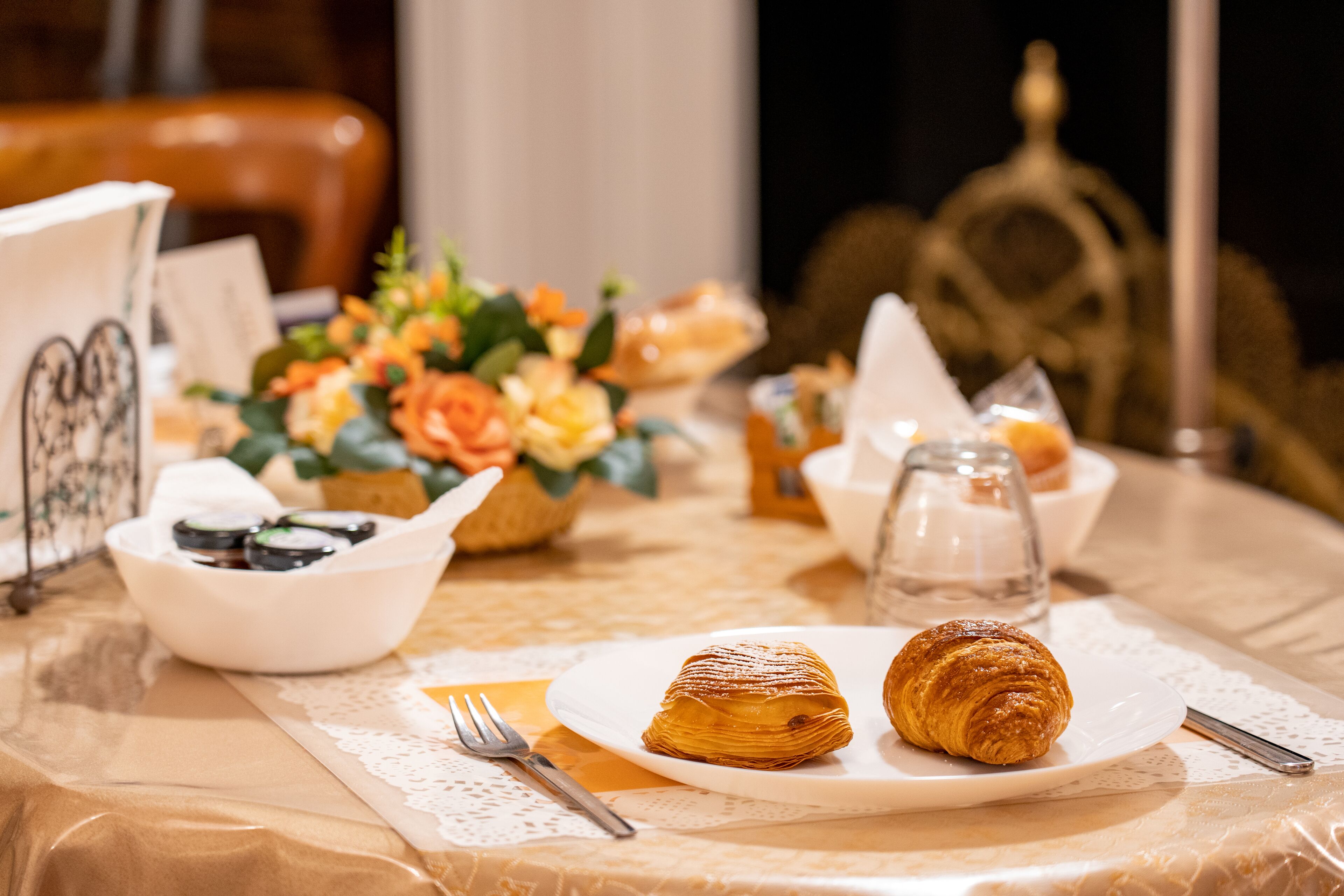 A table set with pastries, a bowl of fruit, and a decorative centerpiece.