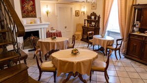 A dining area with round tables, chairs, a chandelier, and a fireplace. - Real Borbone (Caserta)