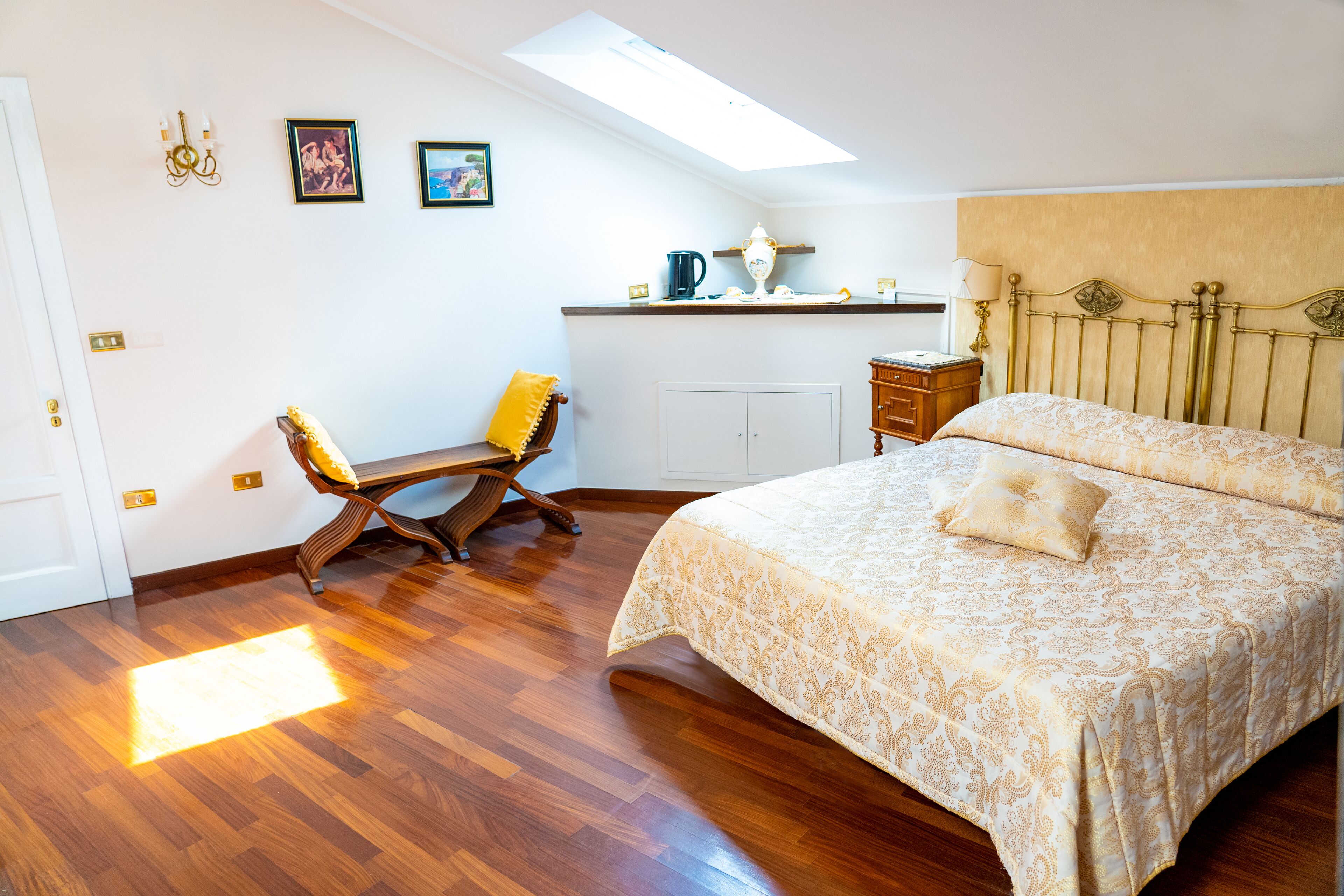 A bedroom with a bed, a desk, and a chair. There is a skylight above the desk.