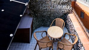 A rooftop terrace with a covered area, a table with chairs, and a view of the surrounding buildings. - Real Borbone (Caserta)