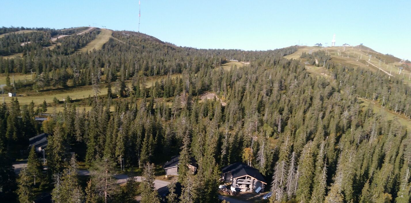 A lodge surrounded by dense forest and hills.