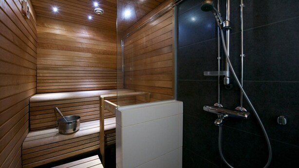 Una sauna con paredes de madera y un área de ducha moderna.