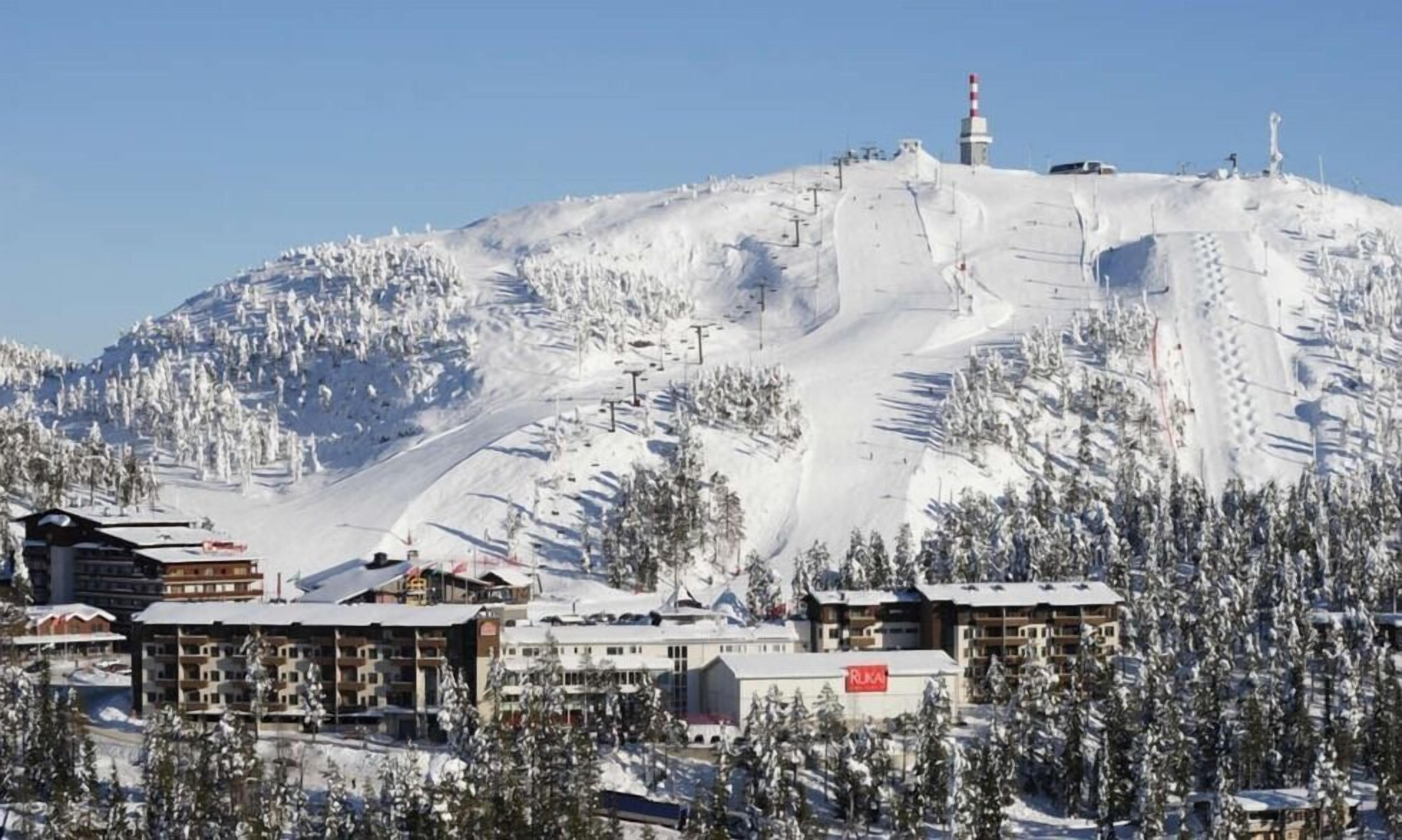 Ein schneebedeckter Berg mit Skiliften und einer Berghütte mit mehreren Gebäuden.