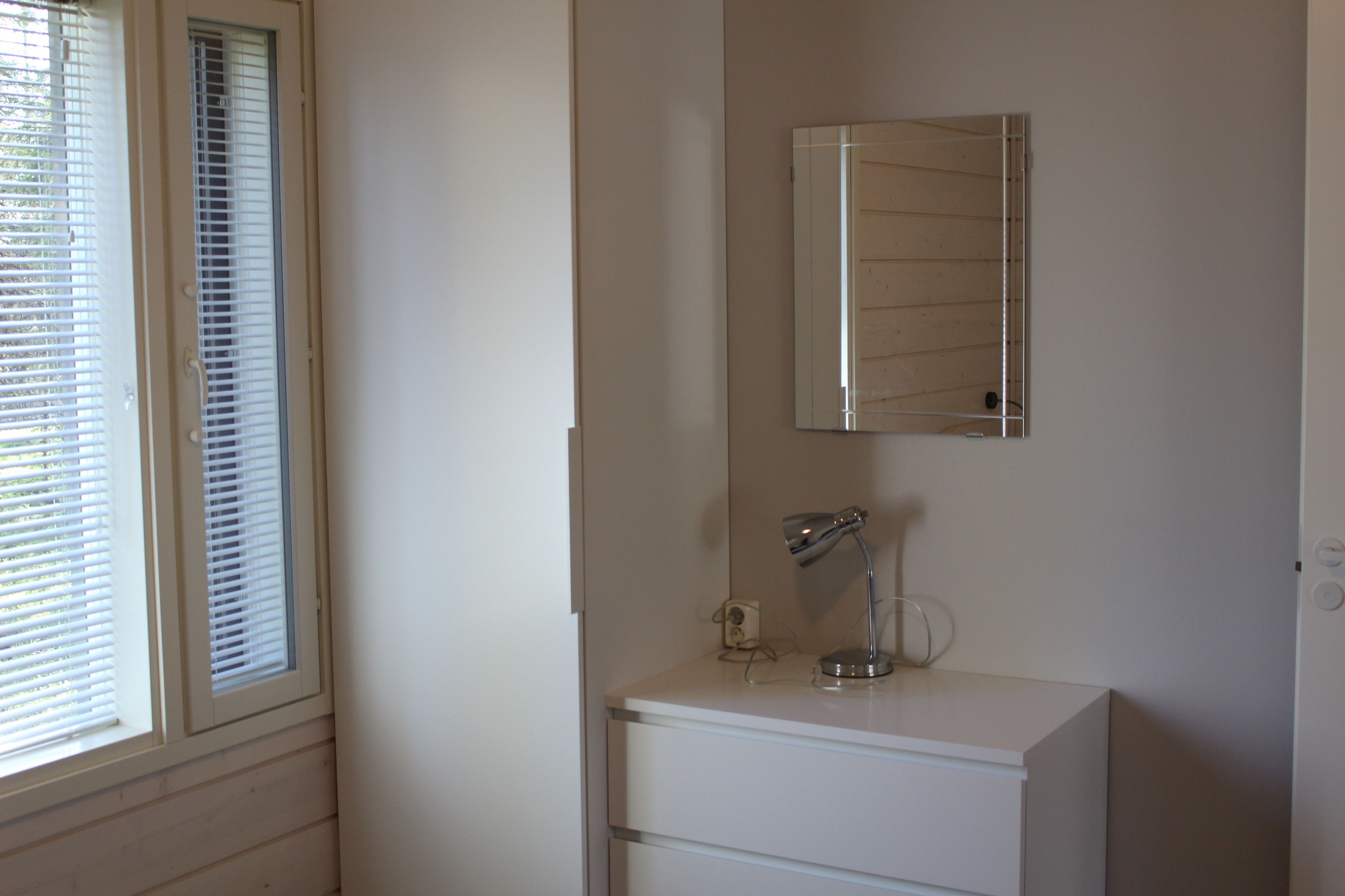 Un bagno con un mobile lavabo bianco, uno specchio e una finestra dotata di persiane.
