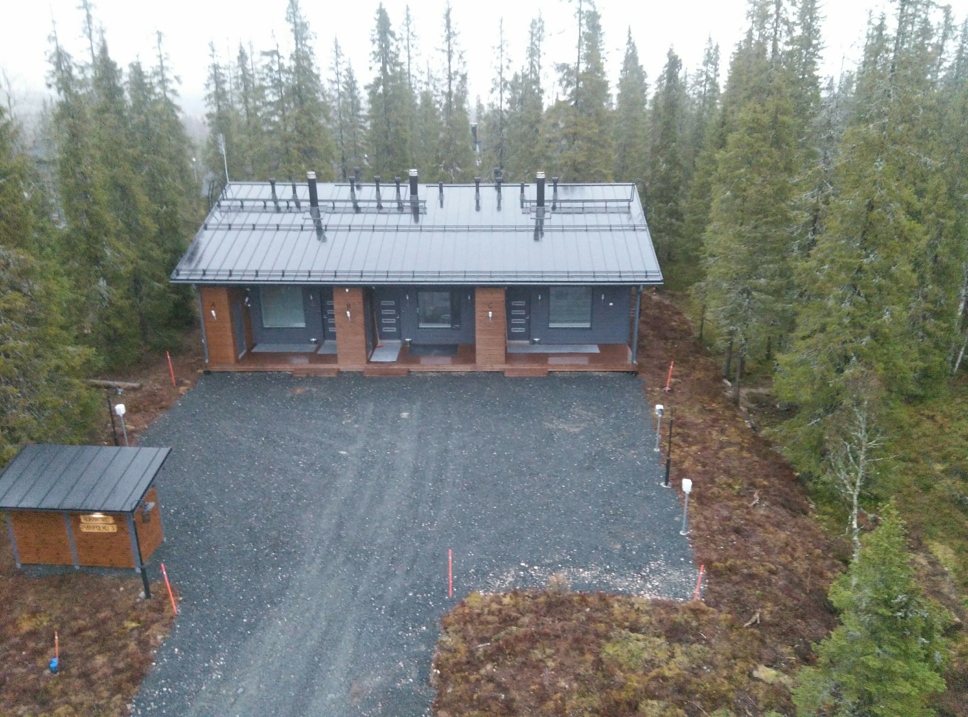 A lodge with a metal roof, two main doors, and a gravel driveway.