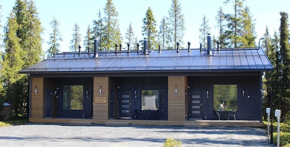 A modern building with a metal roof, large windows, and a gravel driveway.
