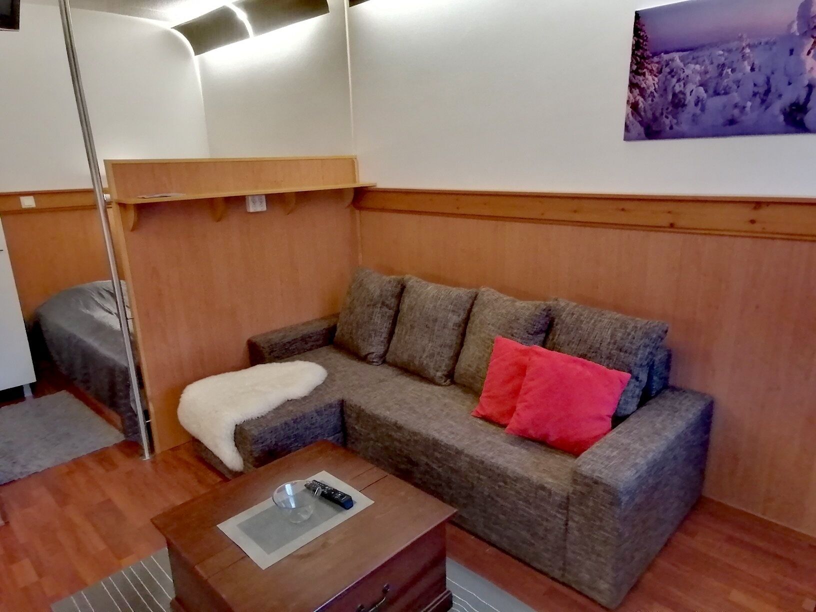 A cozy room with a sofa, a small wooden table, and a wall-mounted shelf.