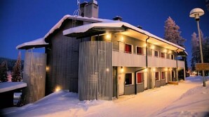 A snow-covered building with a modern design, featuring a balcony and multiple windows. - Vuosselin Helmi (Kuusamo)