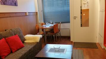 Ein gemütlicher Wohnbereich mit einer Couch, einem Couchtisch und einem Esstisch mit Stühlen.