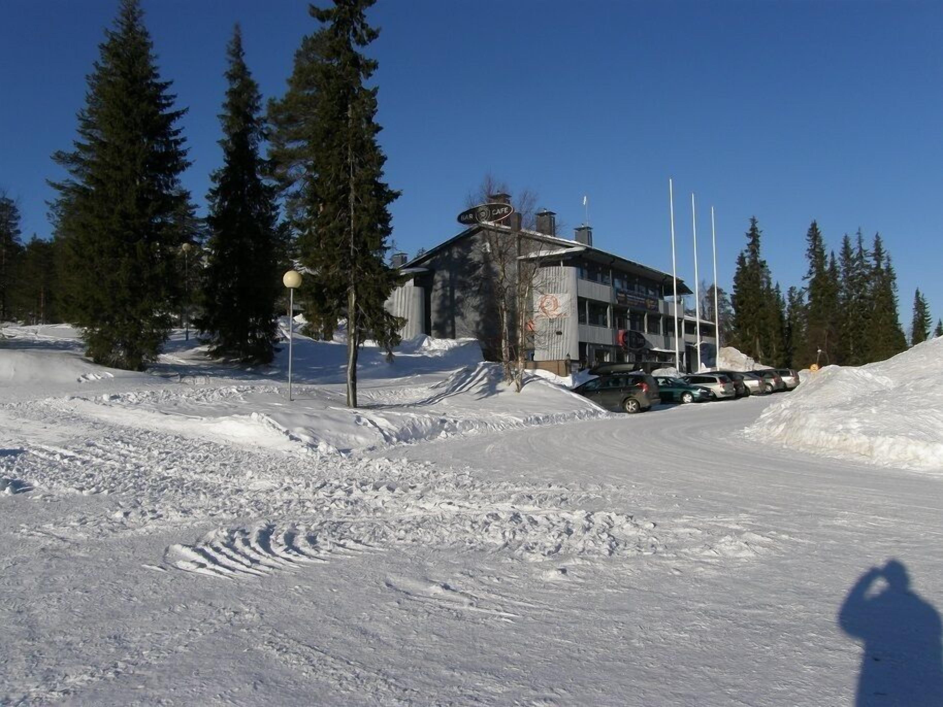 Un bâtiment avec une enseigne indiquant qu’il s’agit d’un café, entouré de neige et d’arbres.
