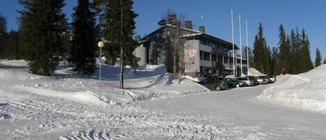 Un bâtiment avec une enseigne indiquant qu’il s’agit d’un café, entouré de neige et d’arbres.
