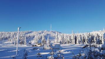 A snowy landscape with a clear blue sky, a few buildings, and a distant tower.