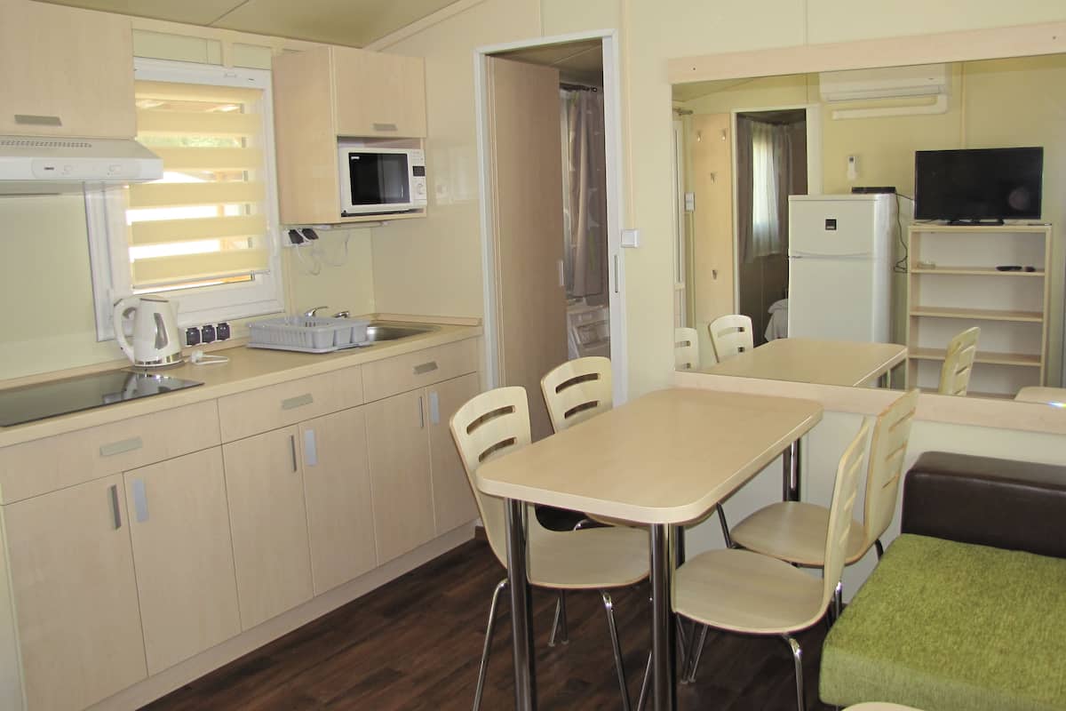 Une petite cuisine équipée d’un micro-ondes, d’une bouilloire et d’un évier. Un coin repas avec une table et des chaises est également à disposition.