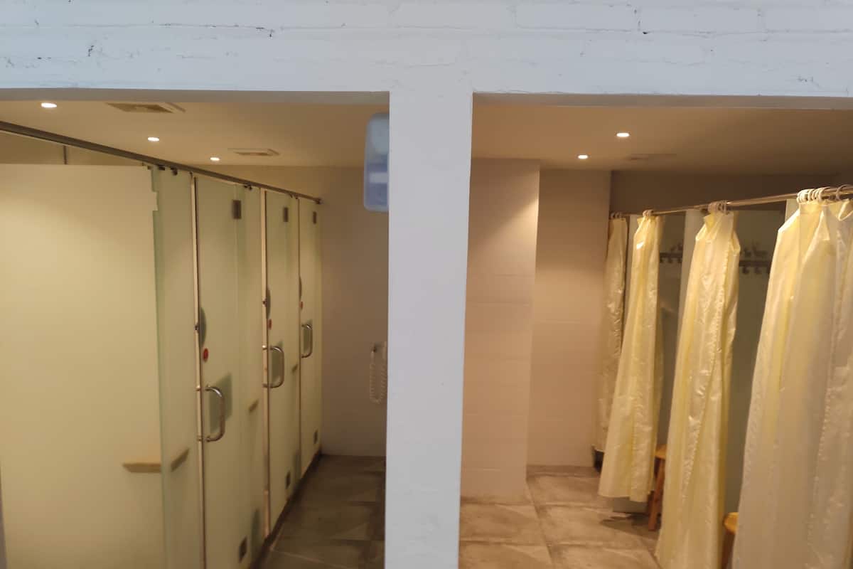 A corridor with glass doors and a shower area with curtains.