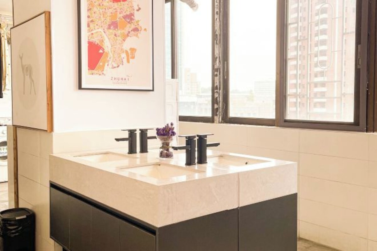 Un baño moderno con un ventanal amplio, un lavabo con dos grifos y un mapa enmarcado en la pared.
