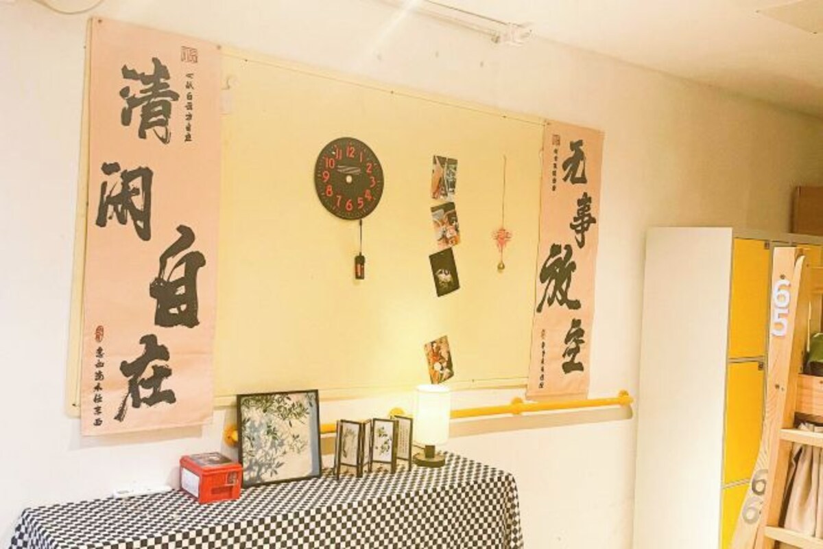 Una habitación con mantel a cuadros, un reloj y caligrafía en la pared.
